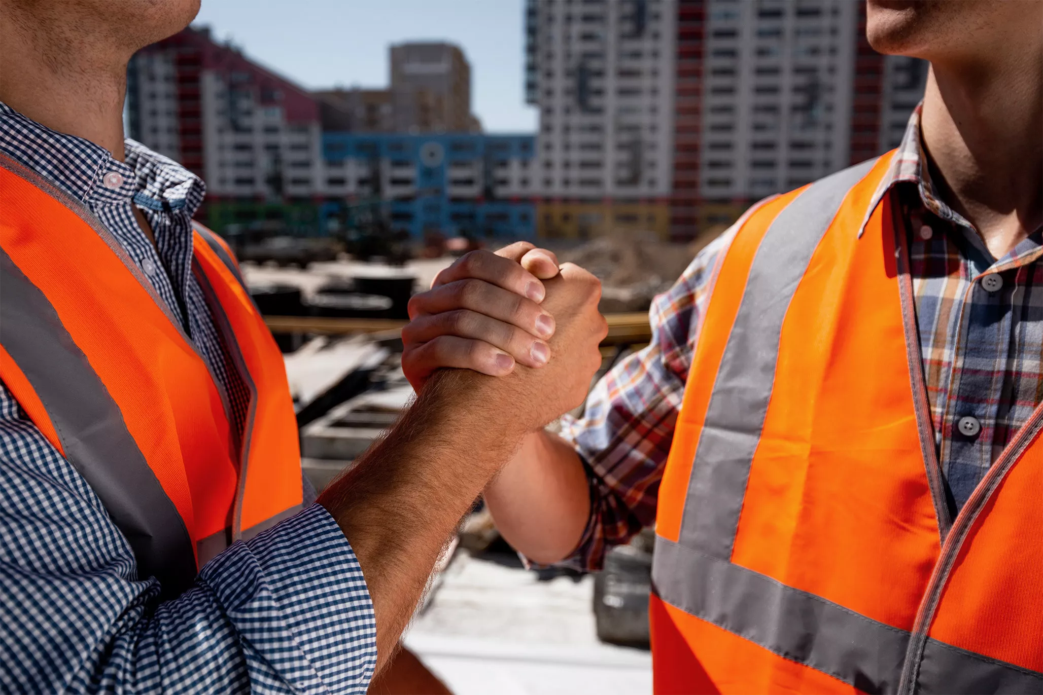 men-dressed-orange-work-vests-shake-hands-building-site-against-background-multi-storey-building.jpg